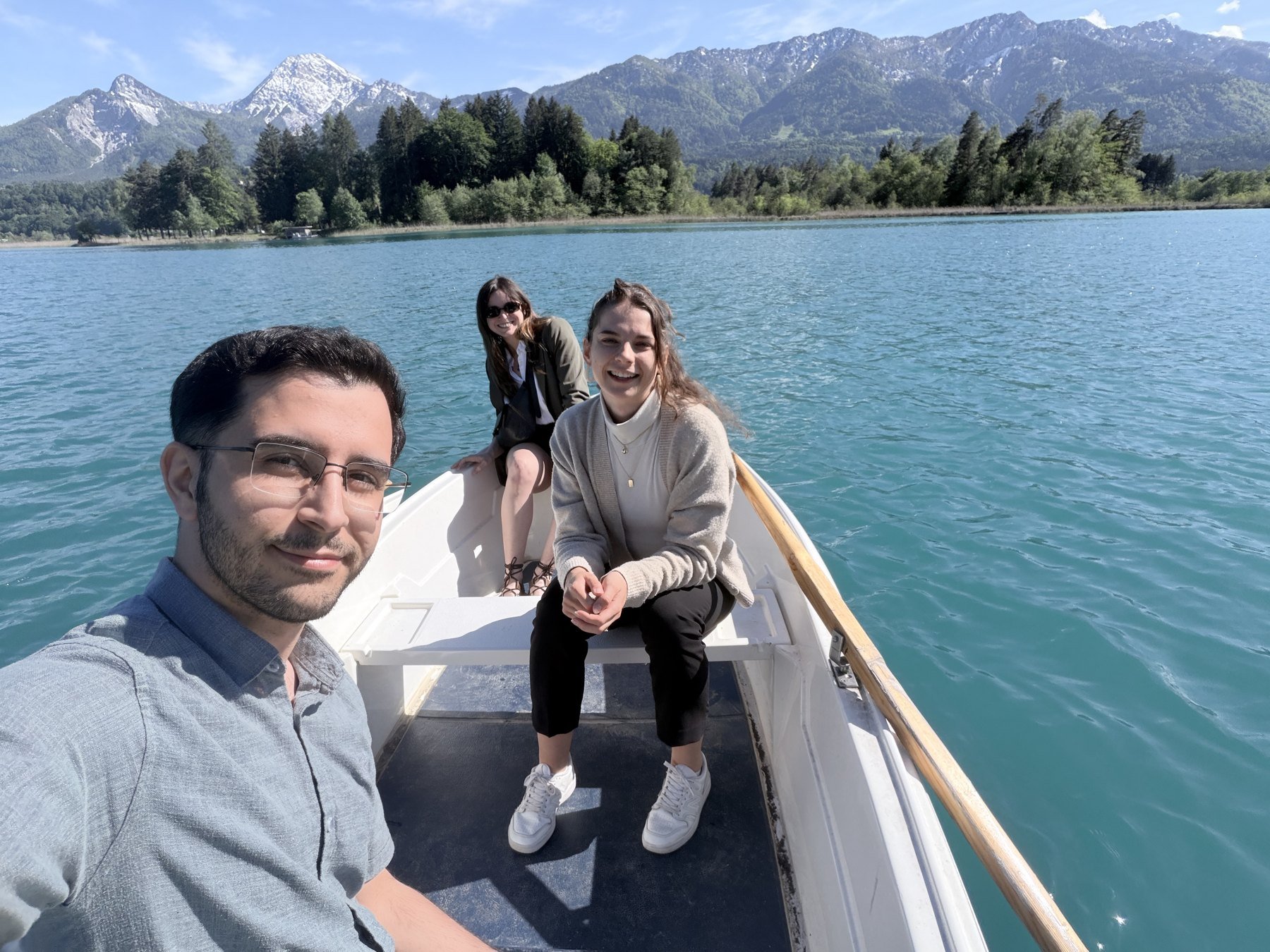 Amir, Camila and Helena in a rowing boat on Lake Faak with the mountains behind